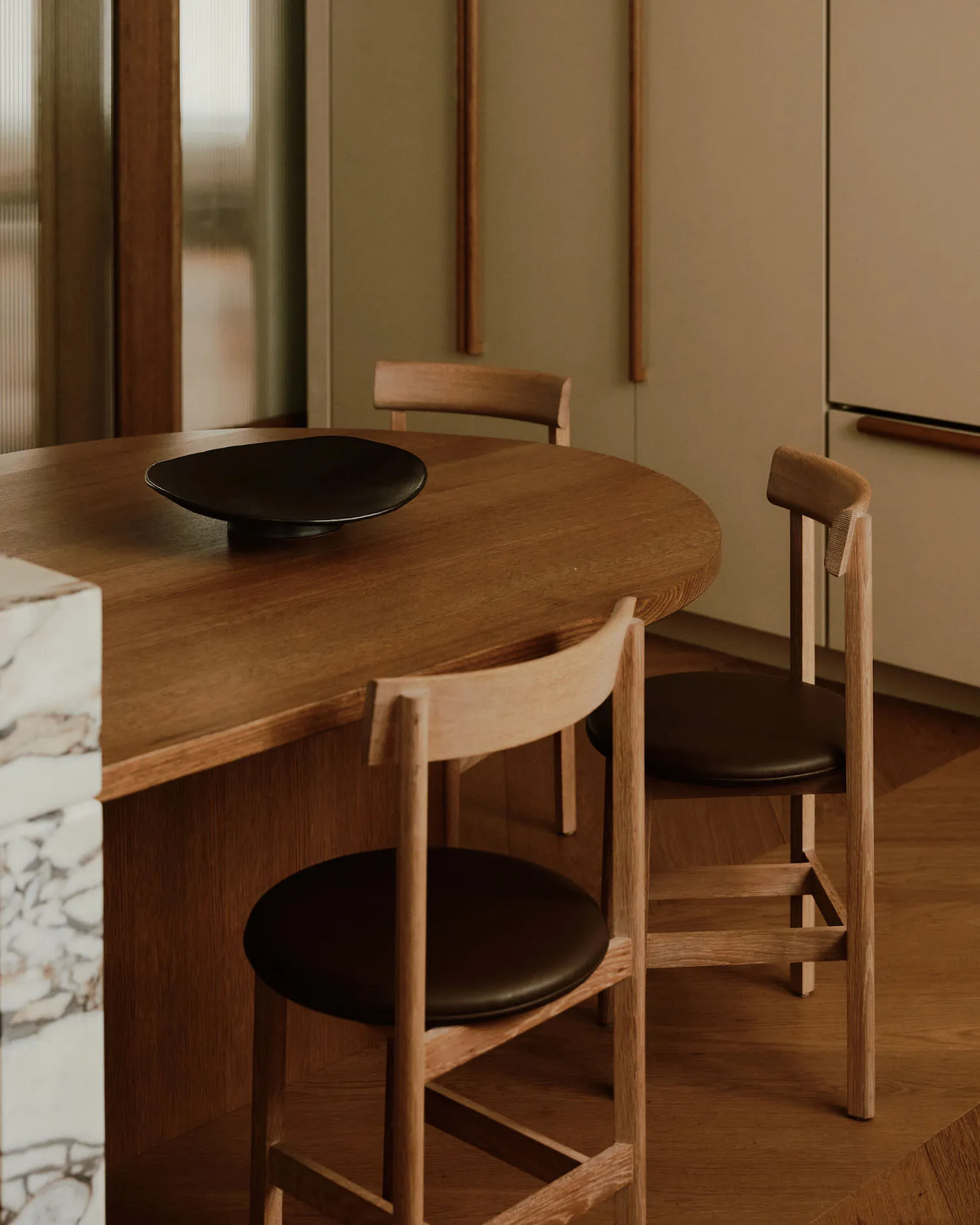 A modern minimalist kitchen with a wooden table and chairs.