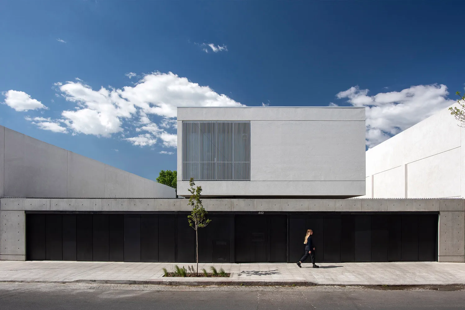 A contemporary office building with concrete walls and a glass facade.