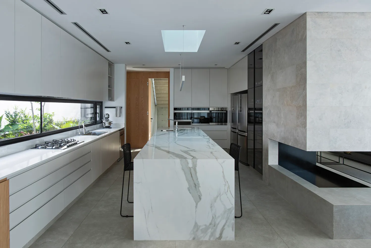 A modern kitchen featuring a marble island, stainless steel appliances, and ample counter space.