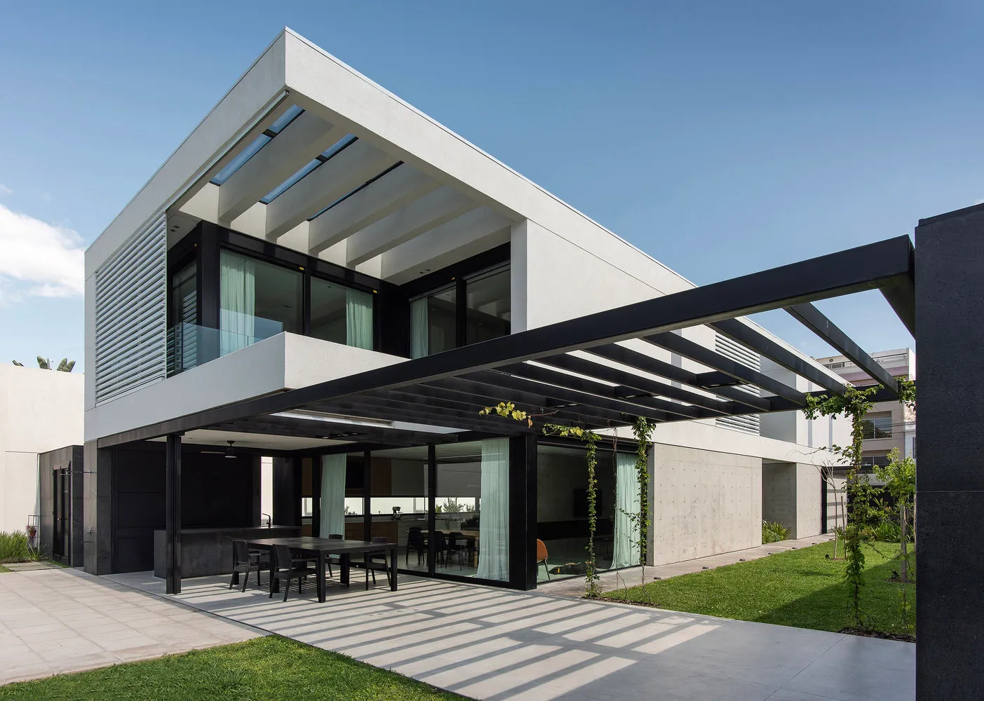 A modern minimalist exterior with concrete walls, glass balconies, and aluminum railings.