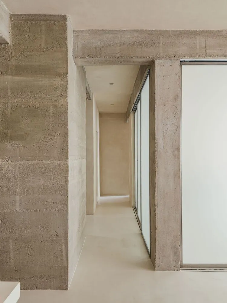 A minimalist corridor with concrete walls, minimal decor, and a long hallway.
