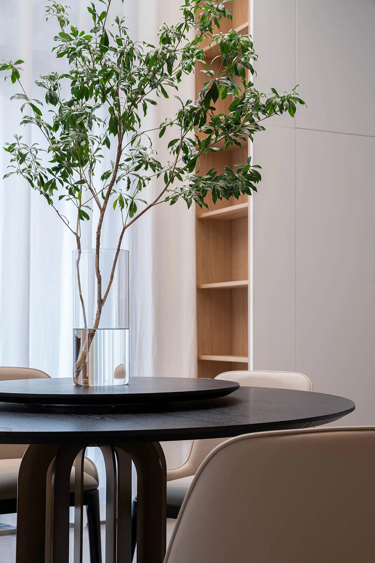 A modern interior design featuring a wooden table with a vase of greenery on top.