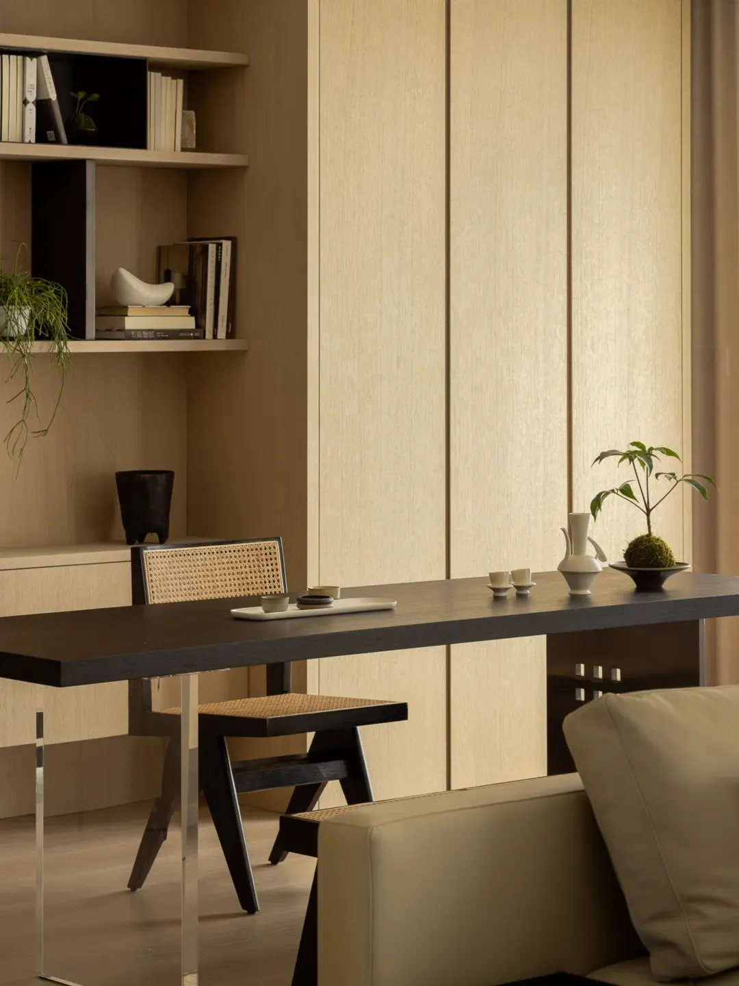 A modern, industrial-style workspace featuring a wooden desk with a black tabletop and a woven stool.