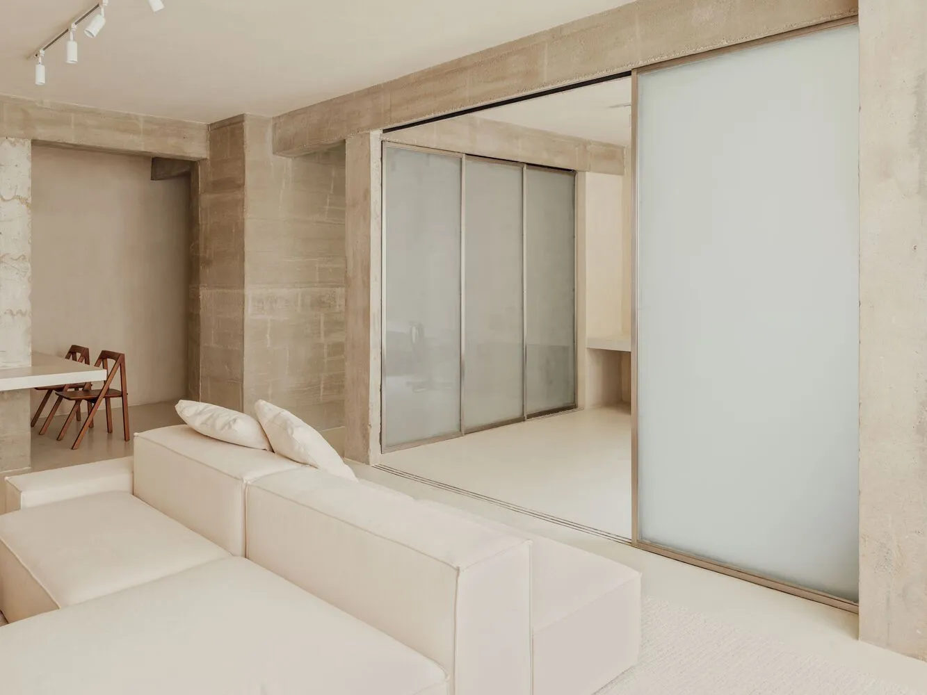 Modern minimalist living room with a white concrete couch and a sleek, futuristic design.