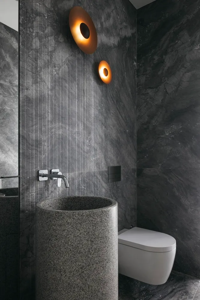 Modern bathroom with grey granite sink, toilet, and wall lights