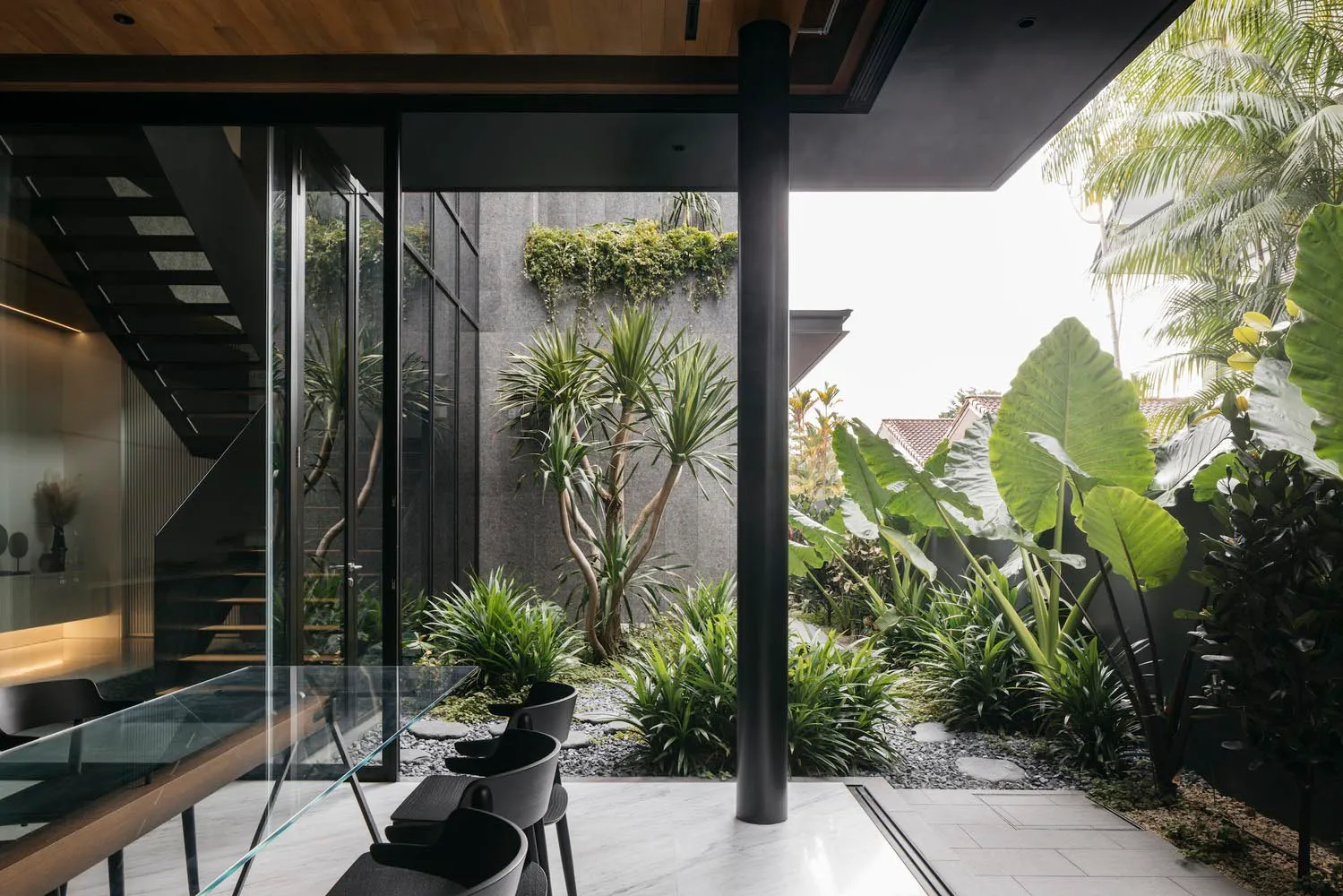 Modern interior living room with concrete walls, glass walls, and tropical plants