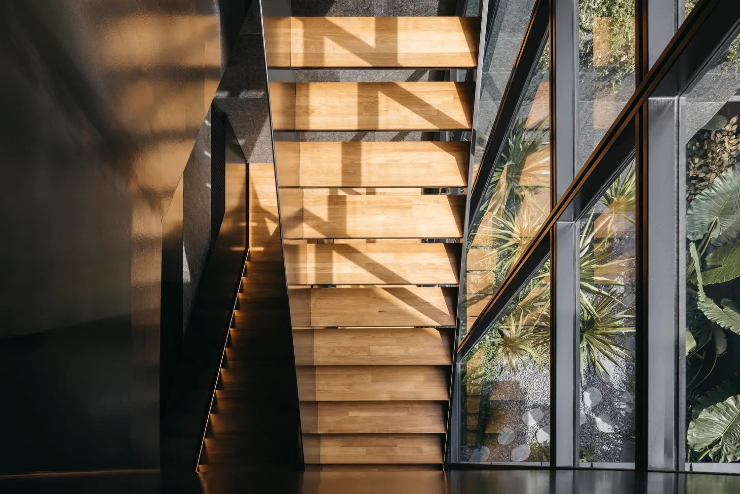 A modern library interior with wooden stairs and glass walls.