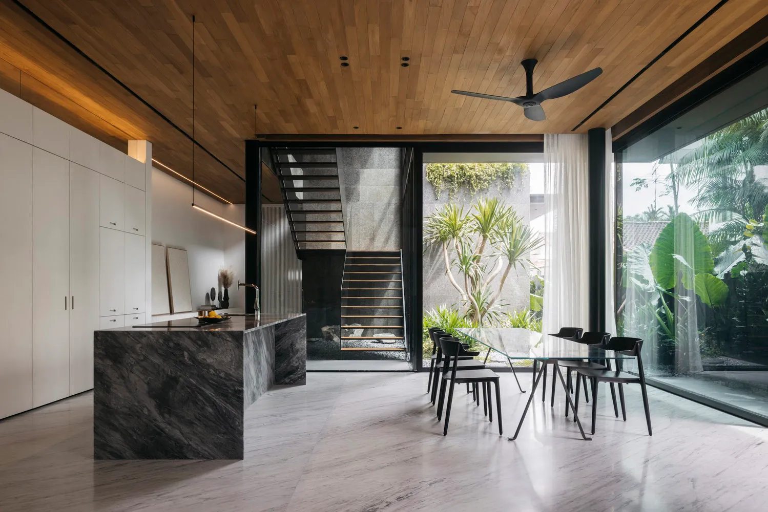 Modern residential interior with marble kitchen island, wooden ceiling, and glass walls