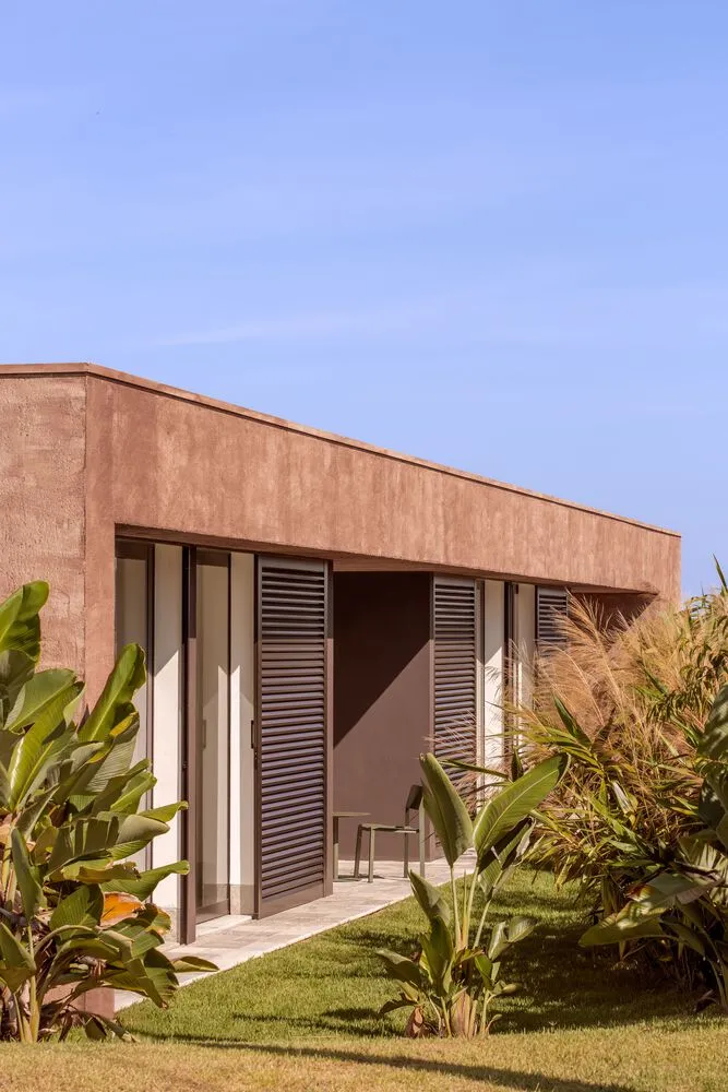 Modern residential exterior featuring concrete walls and metal shuttered windows.