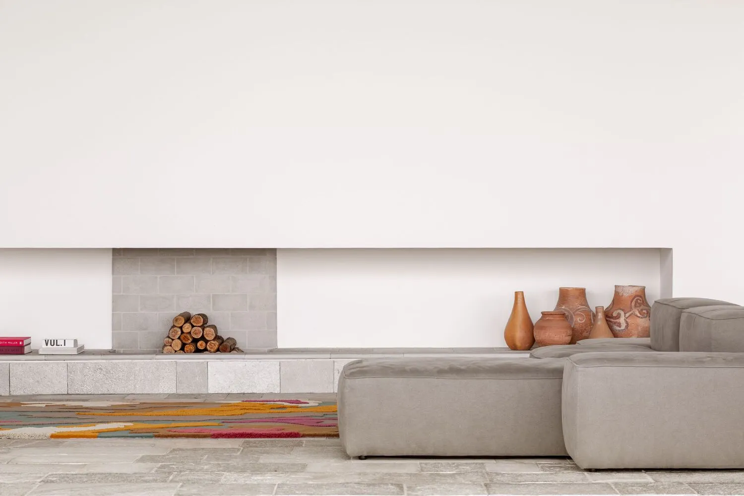 A minimalist living room featuring concrete furniture and soft textiles.