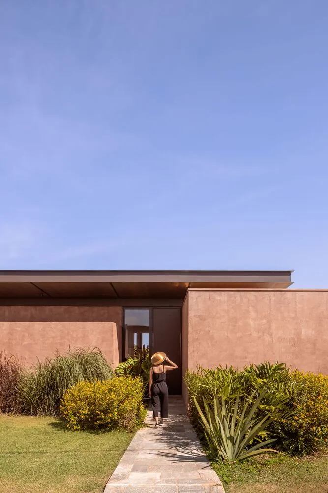 A minimalist residential exterior featuring concrete walls and large glass windows.