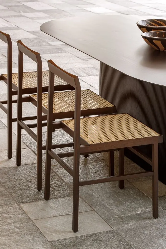 Modern dining room featuring cane woven seating and dark wood dining table.