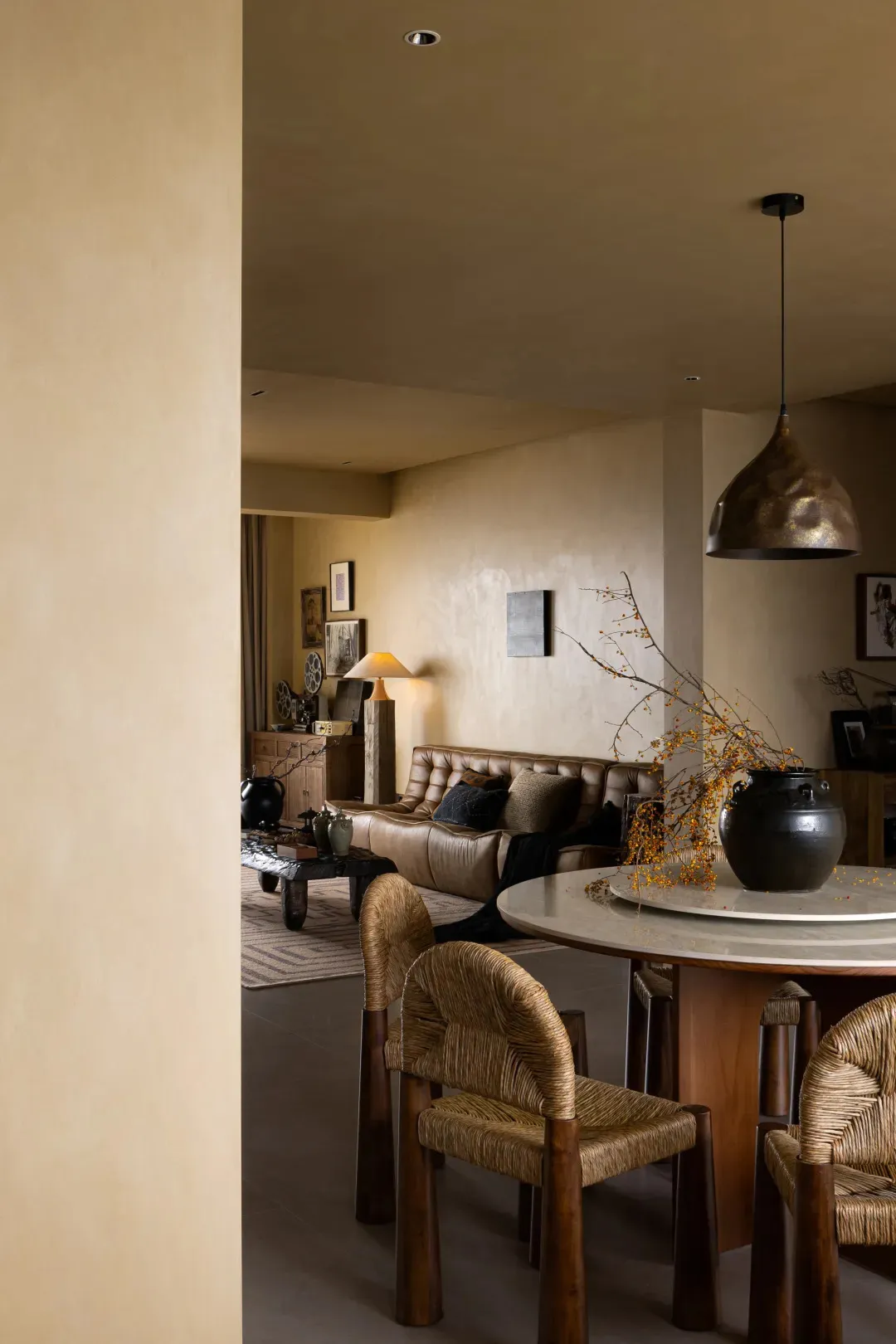 Modern living room featuring a marble table, leather sofa, and woven chairs.