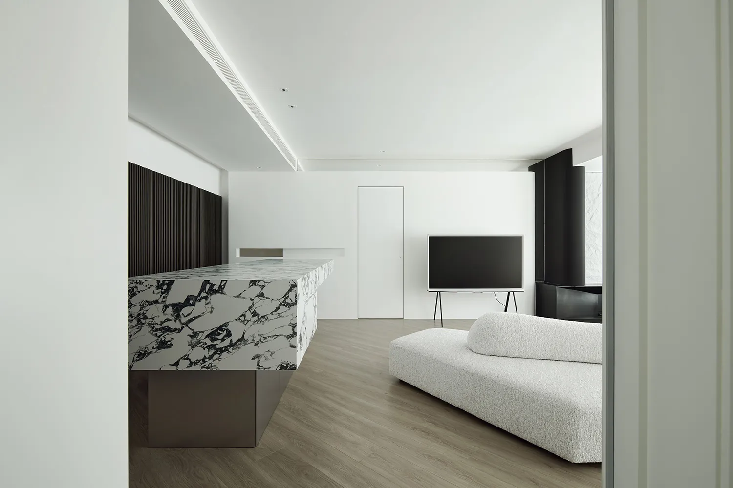 A modern living room featuring a sleek, minimalist design with a marble countertop and a stylish, textured sofa.