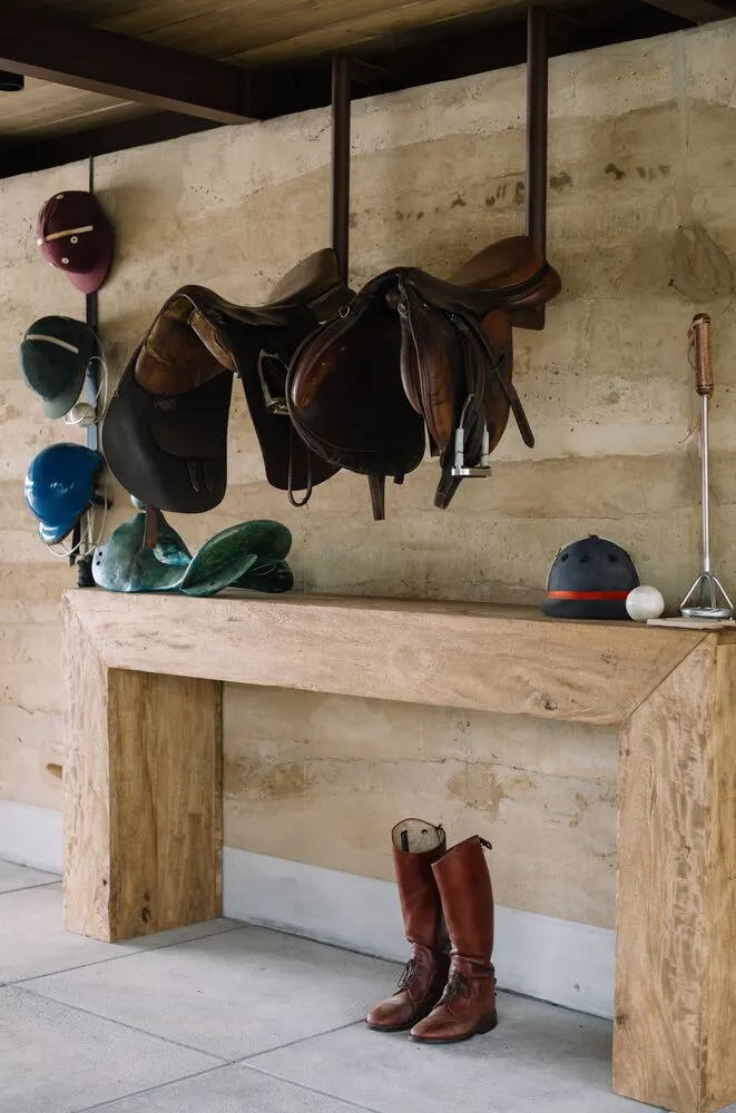 A wooden shelf showcasing various equestrian equipment and supplies within a stable environment.