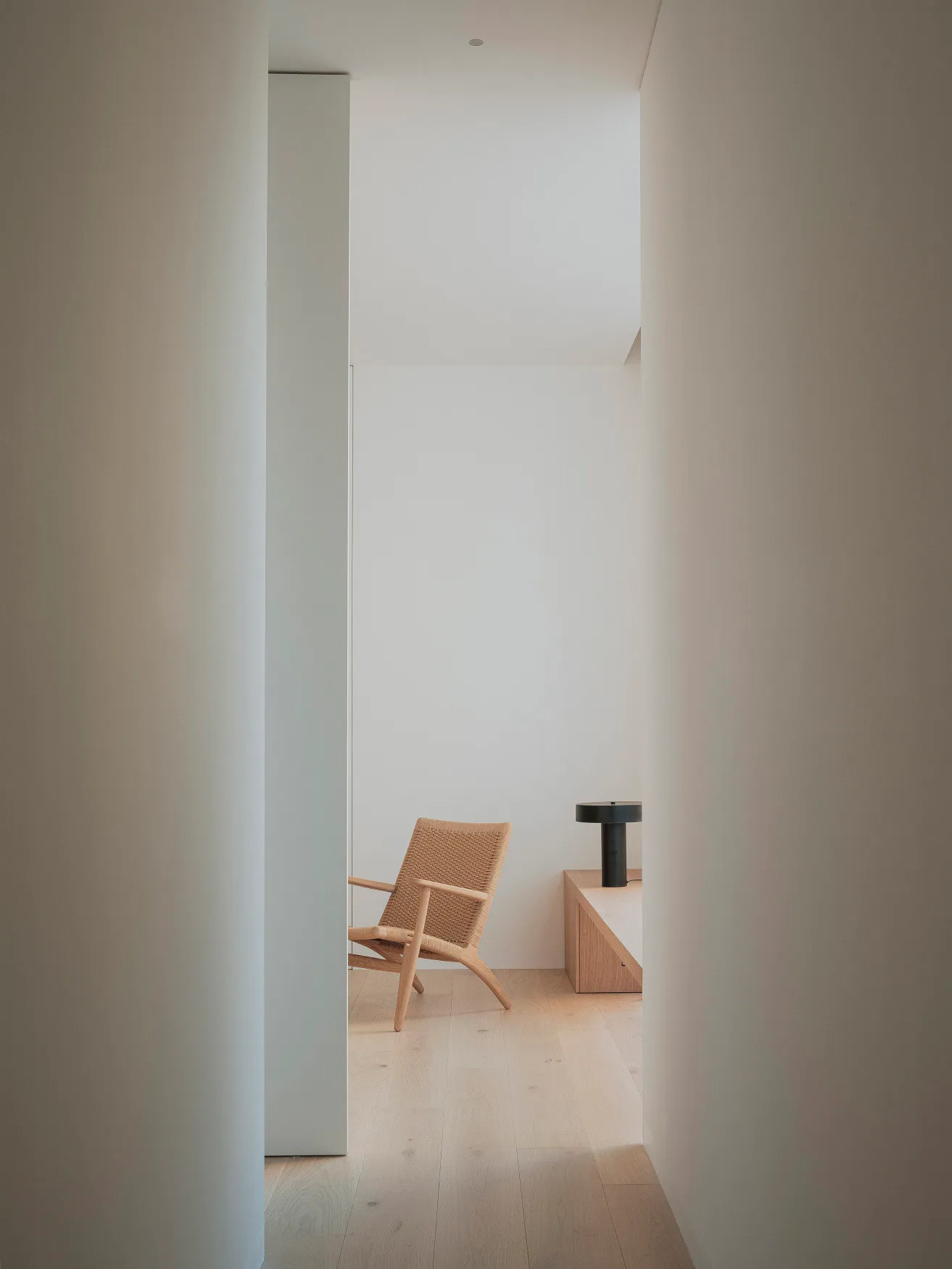 A minimalist interior with a wooden chair against a wall.