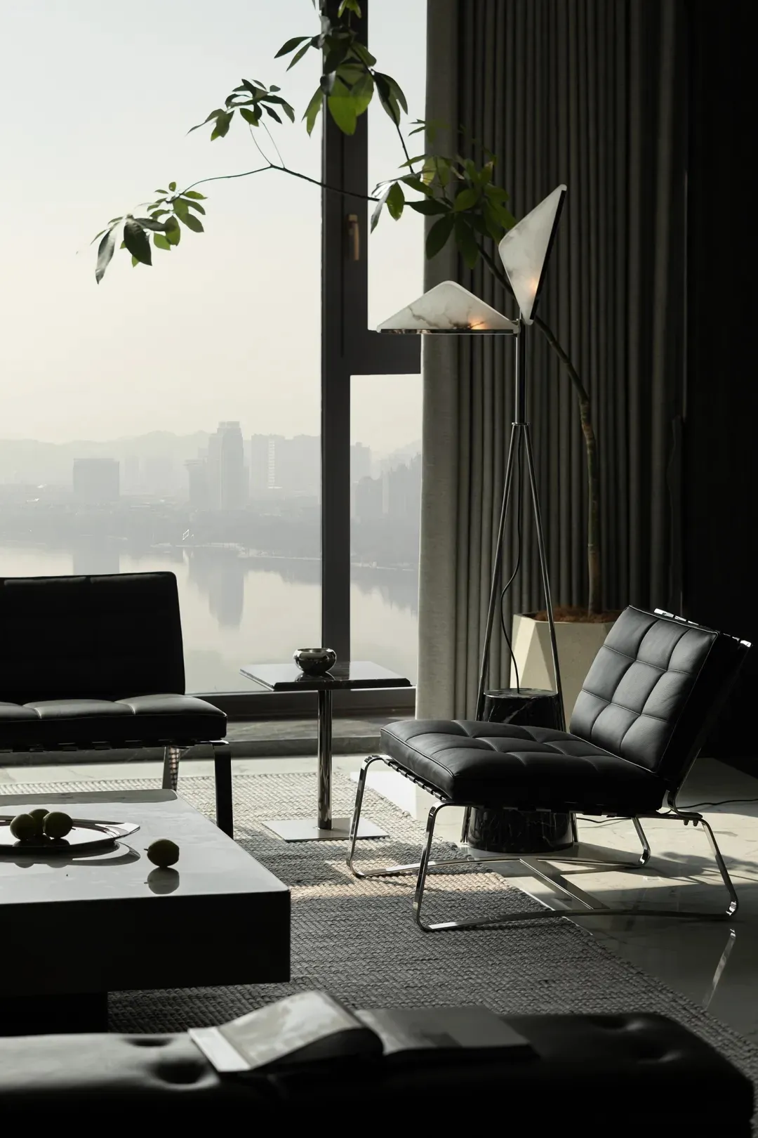 A sleek, minimalist living room featuring leather furniture, marble accents, and a glass coffee table.