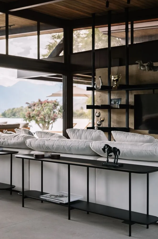 A modern living room with minimalist furniture, white cushions, and a sleek black console table.