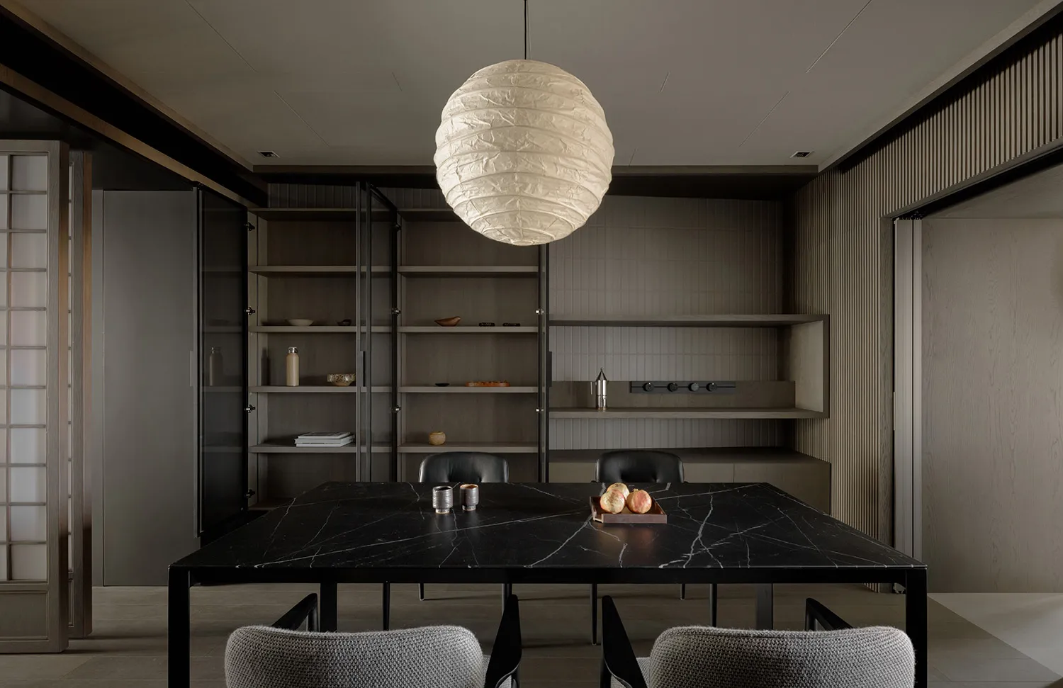 A minimalist dining room featuring a black marble table and fabric upholstered chairs.