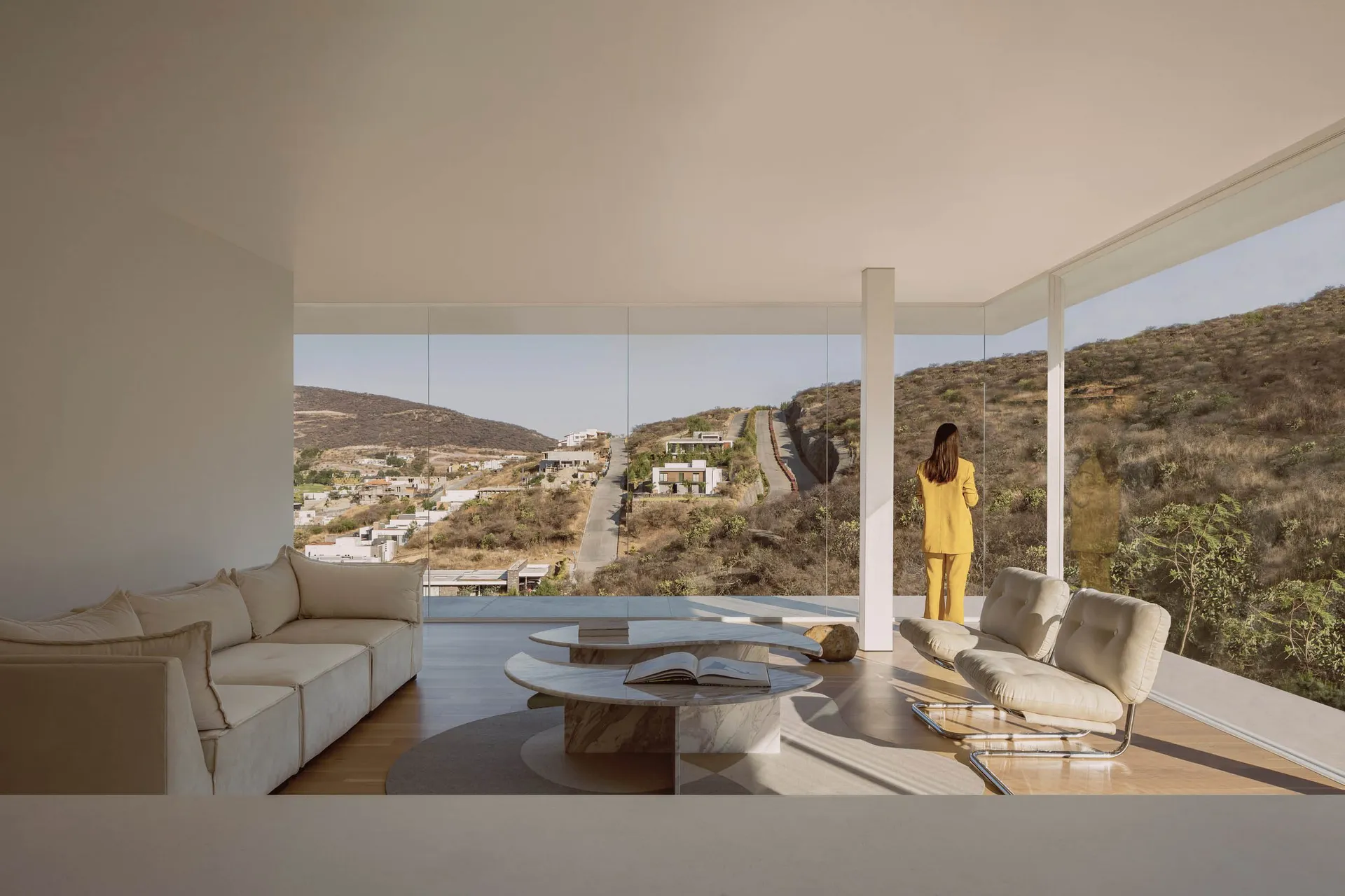 A minimalist residential interior with a view of hills through glass walls.