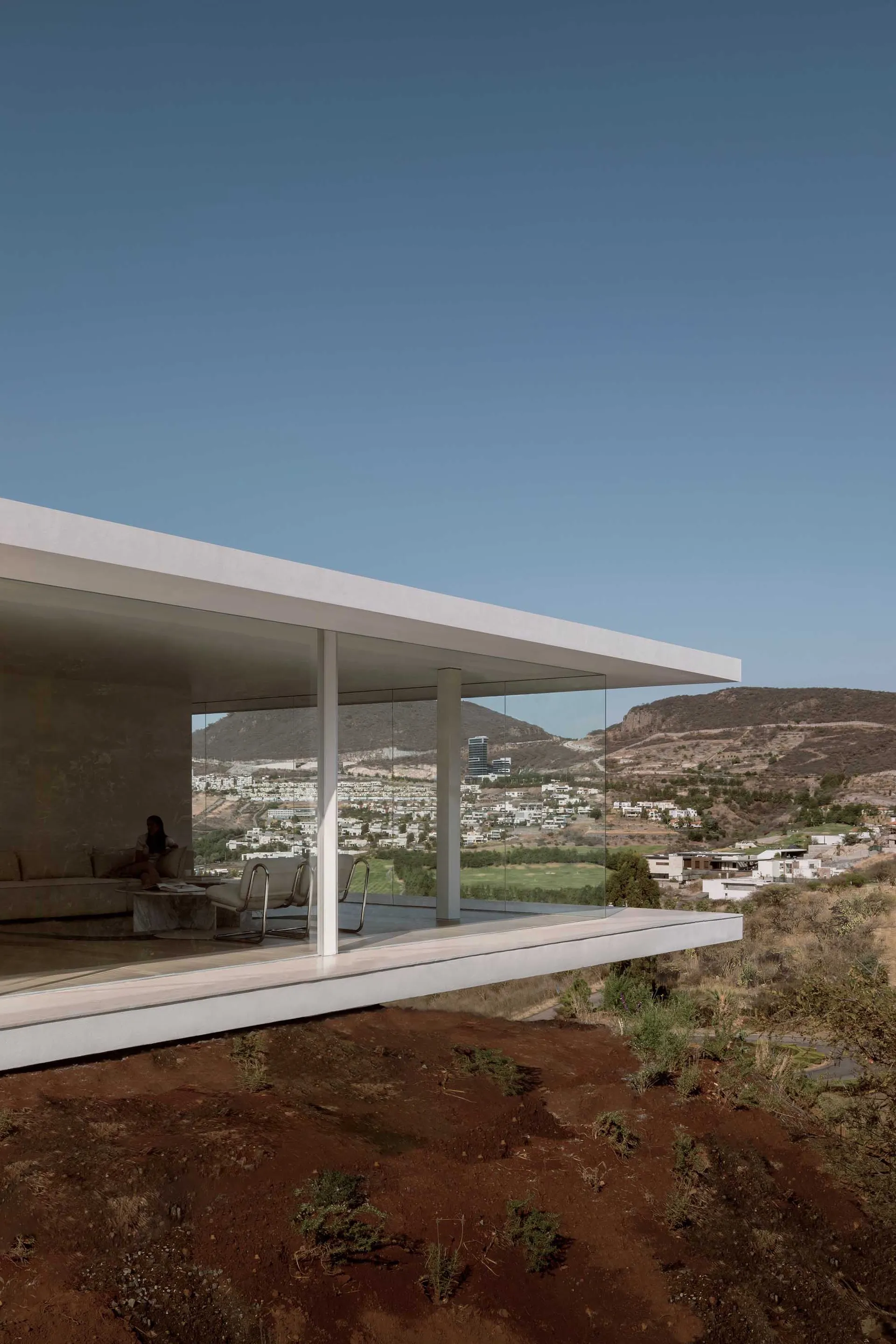 Modern building with glass walls overlooking a scenic landscape.