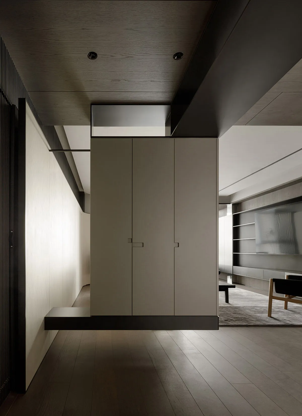 Modern apartment interior with dark wood paneling and white cabinet doors.