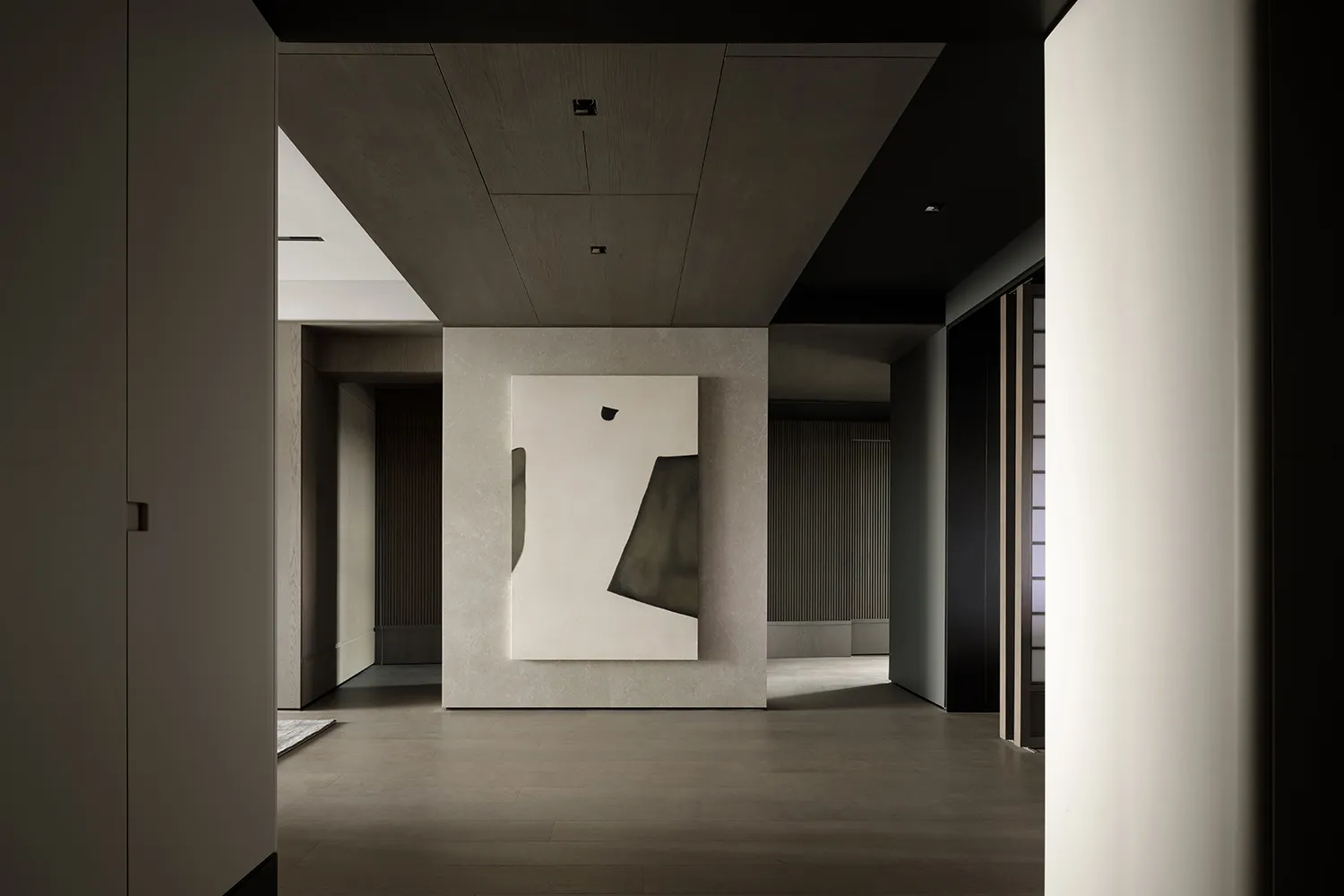 A modern interior featuring minimalist design with a prominent minimalist sculpture on a concrete wall.
