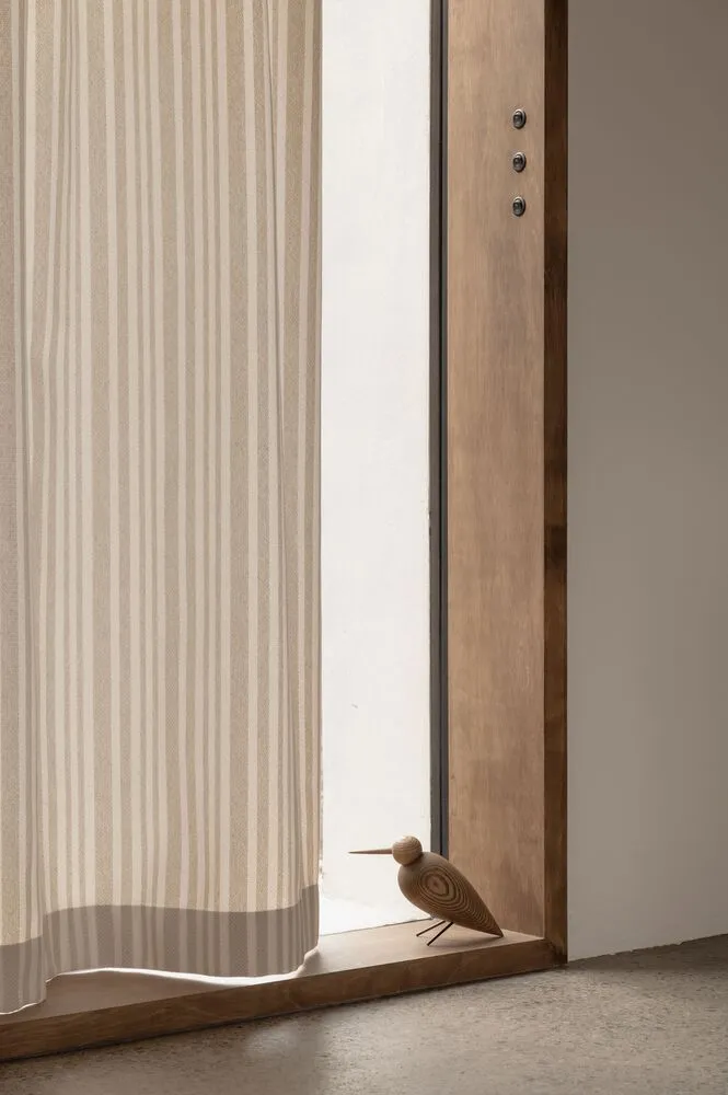 A minimalist doorway featuring a wooden door and a textured curtain, showcasing modern, clean design.