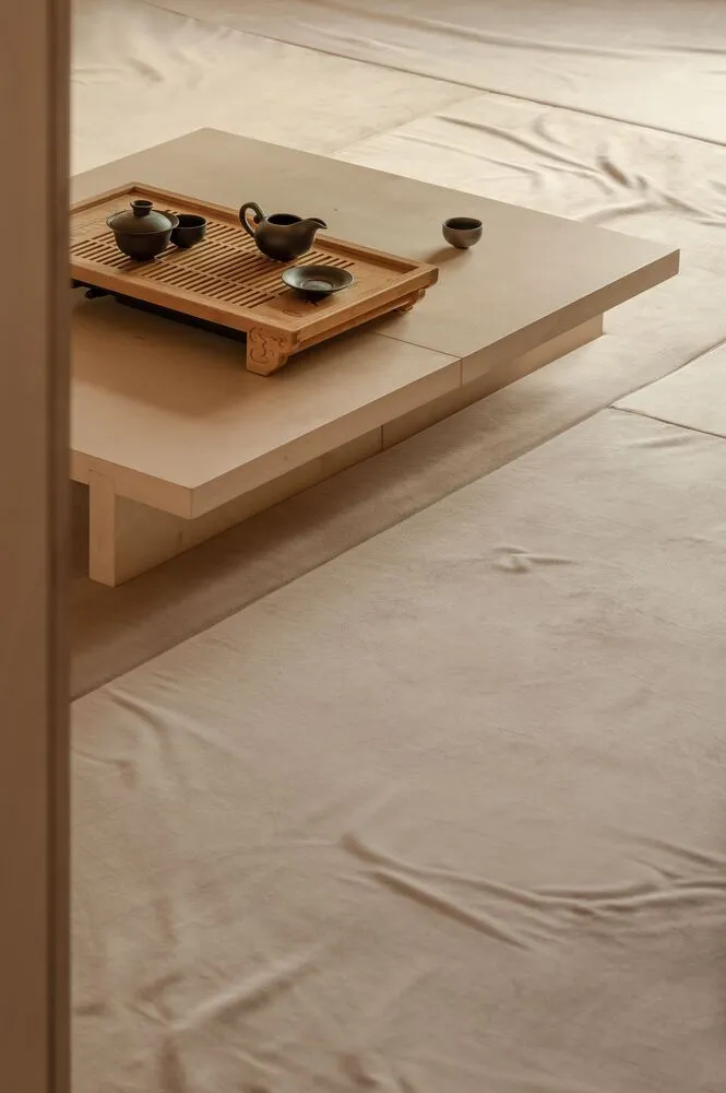 A minimalist space with a wooden floor and low wooden table.