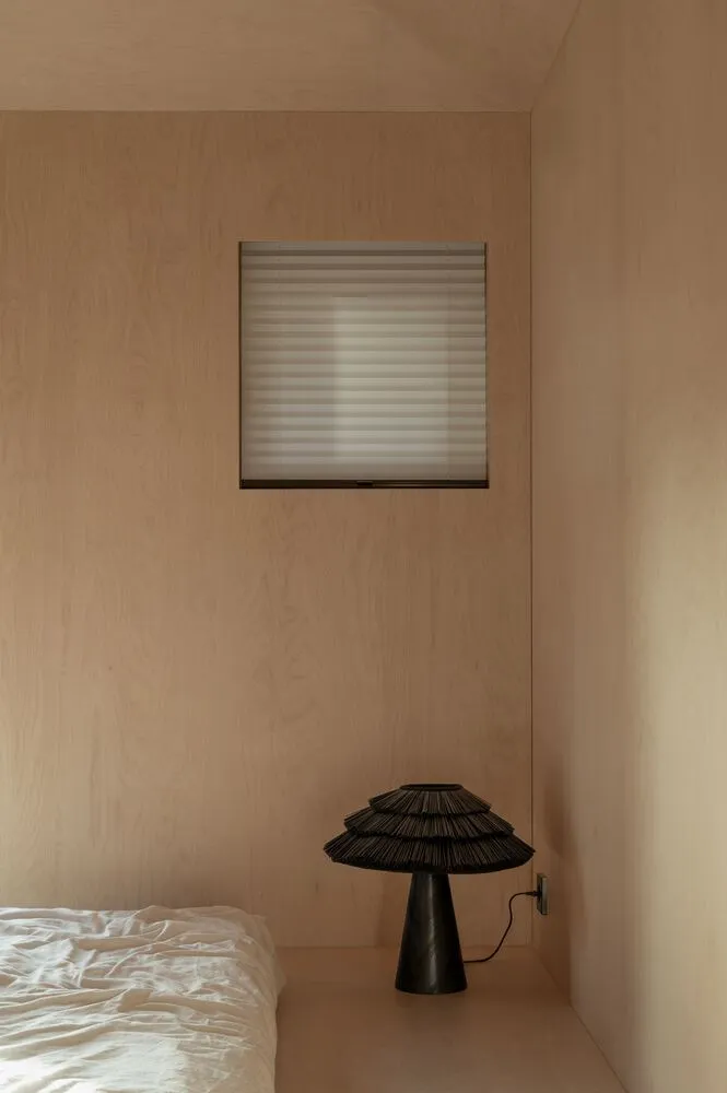 Minimalist bedroom with a black lamp and wooden walls.