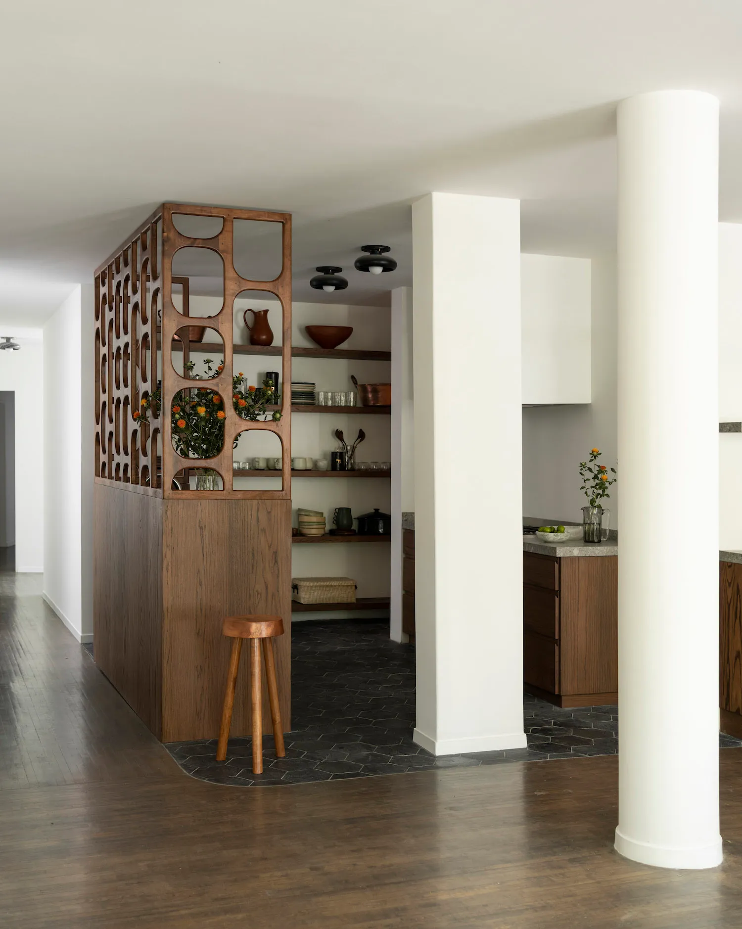 A modern kitchen with an open space design and wooden features, including white cabinets and brown wooden accents.
