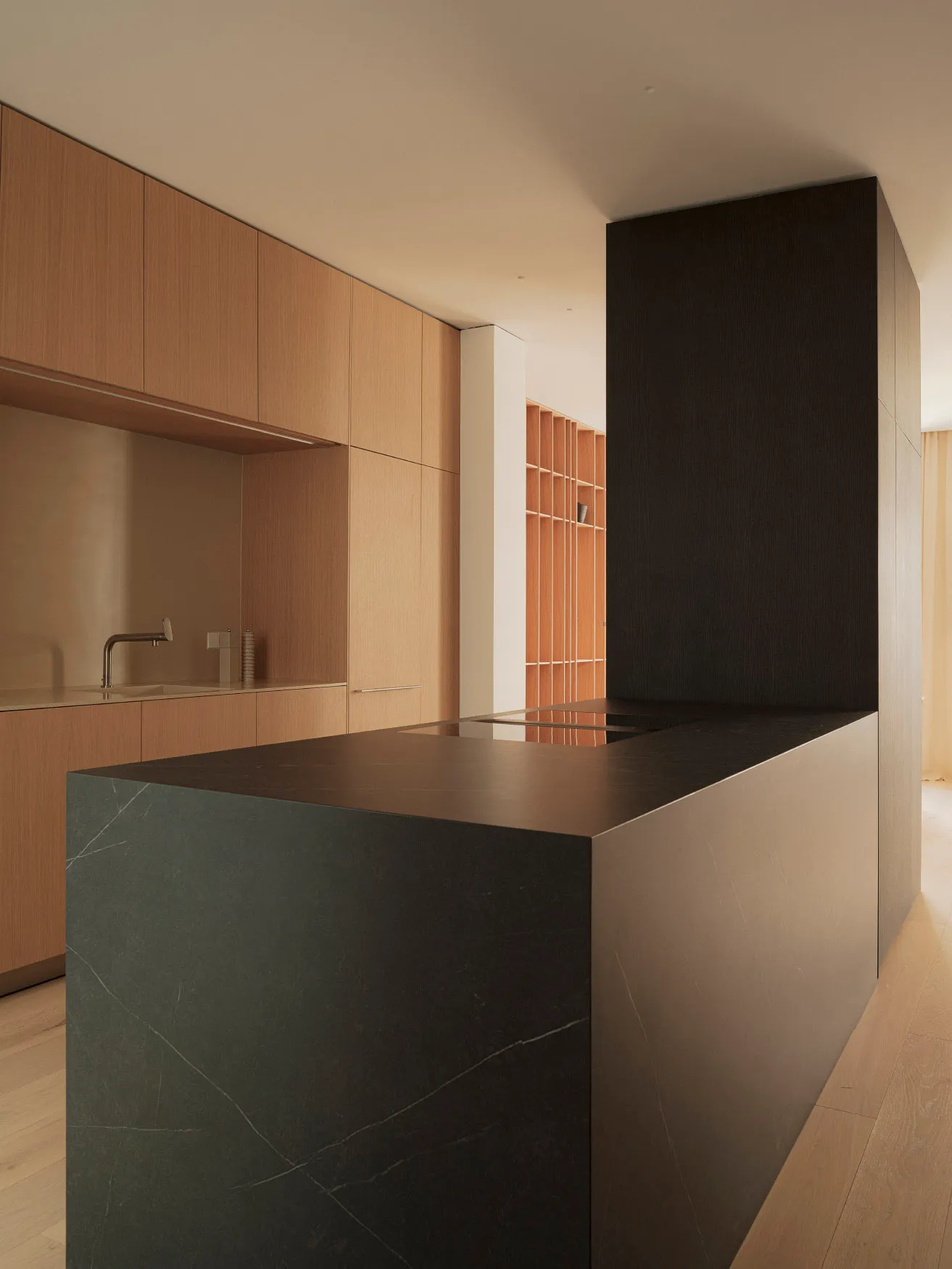 A modern minimalist kitchen with black stone island and wooden panels
