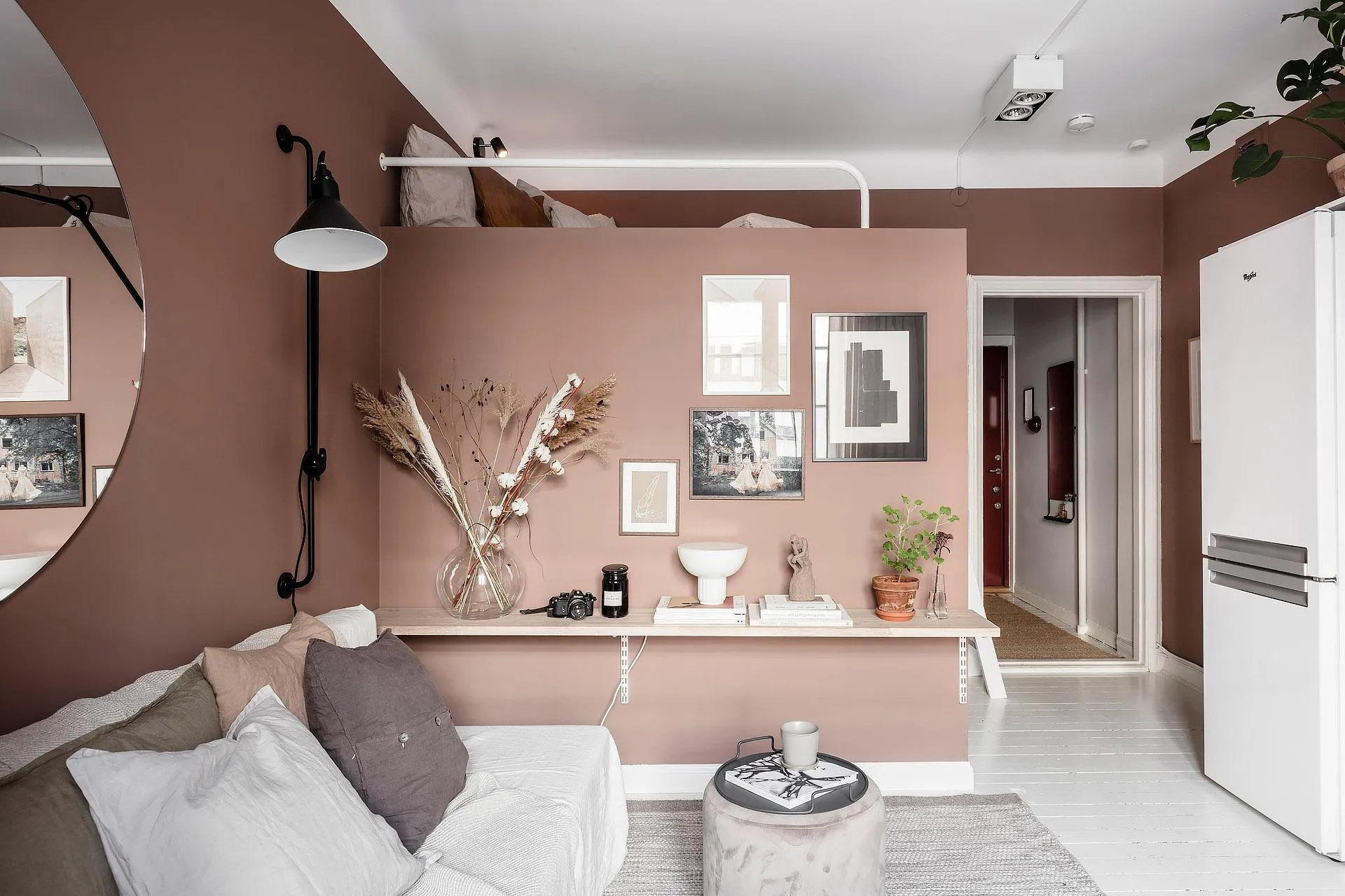 A minimalist living room with white wood finishes, featuring a white sofa adorned with white and gray pillows, a coffee table