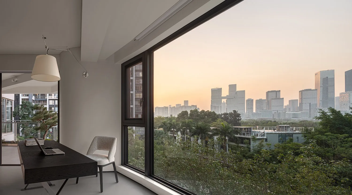Modern interior with glass windows and wooden furniture looking out over a cityscape.