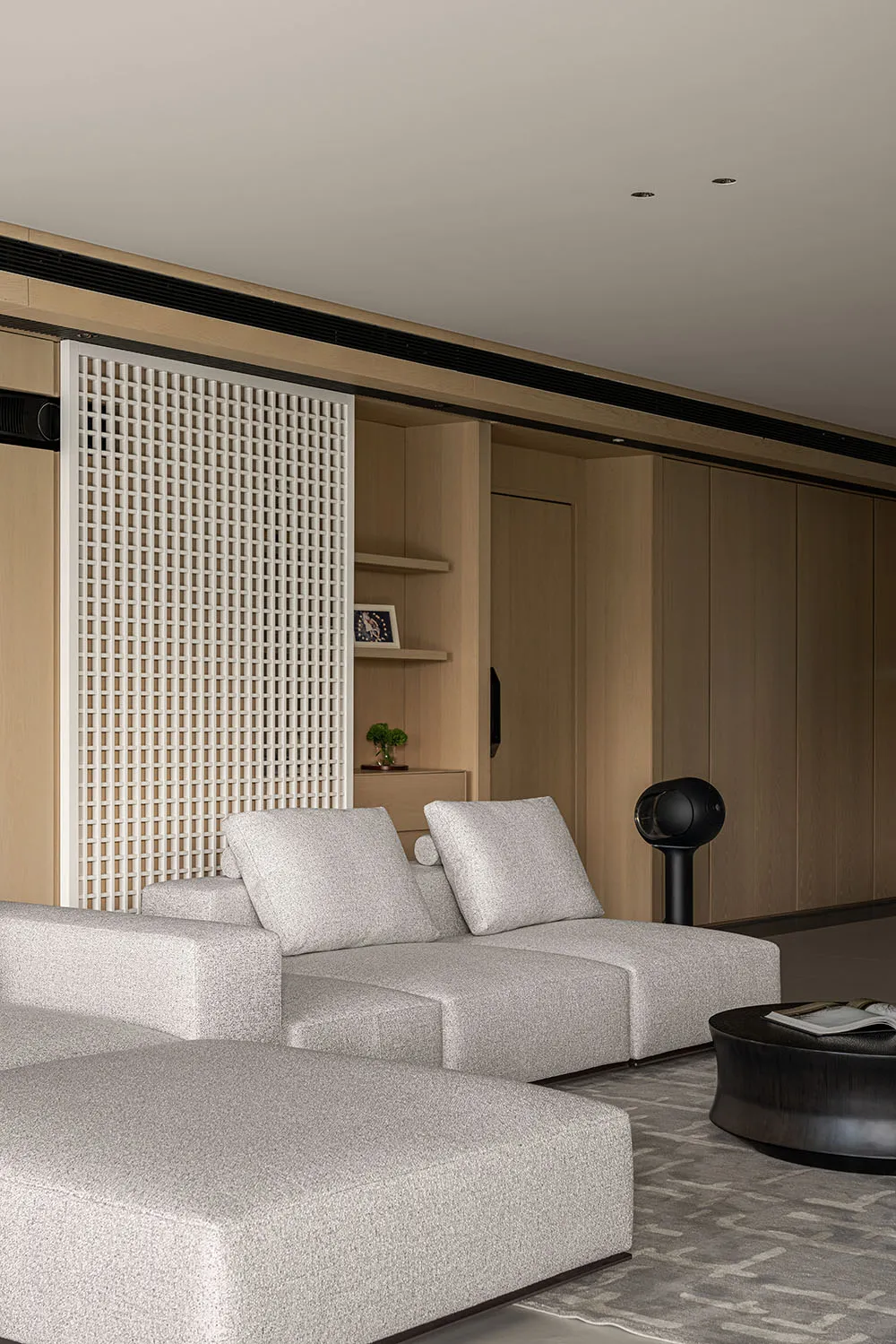 Modern living room with open concept, featuring a light-colored fabric sectional sofa and minimalist design elements.
