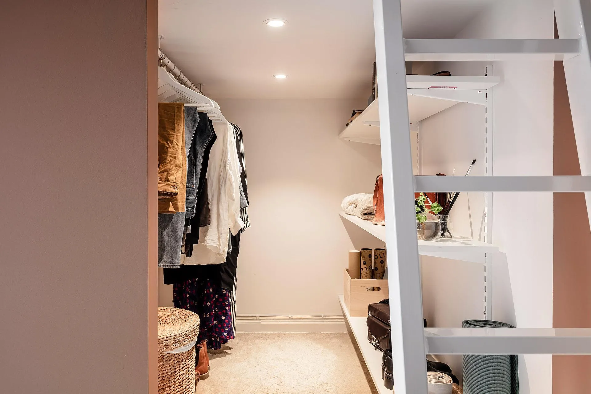 A minimalist closet with white metal shelving for clothing storage.