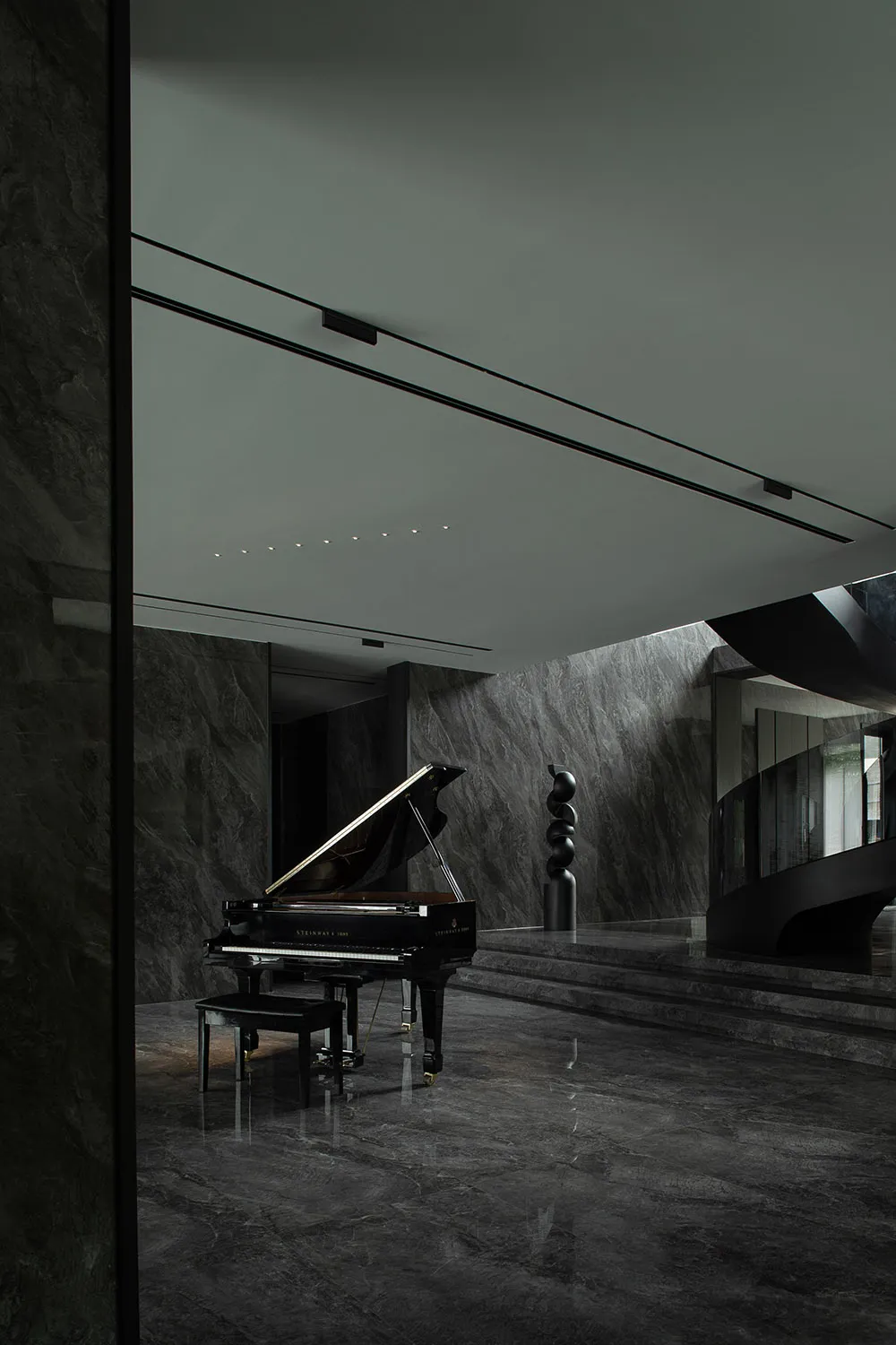 A sleek, minimalist piano room with black marble floors and walls, featuring a black grand piano with a black metal column in
