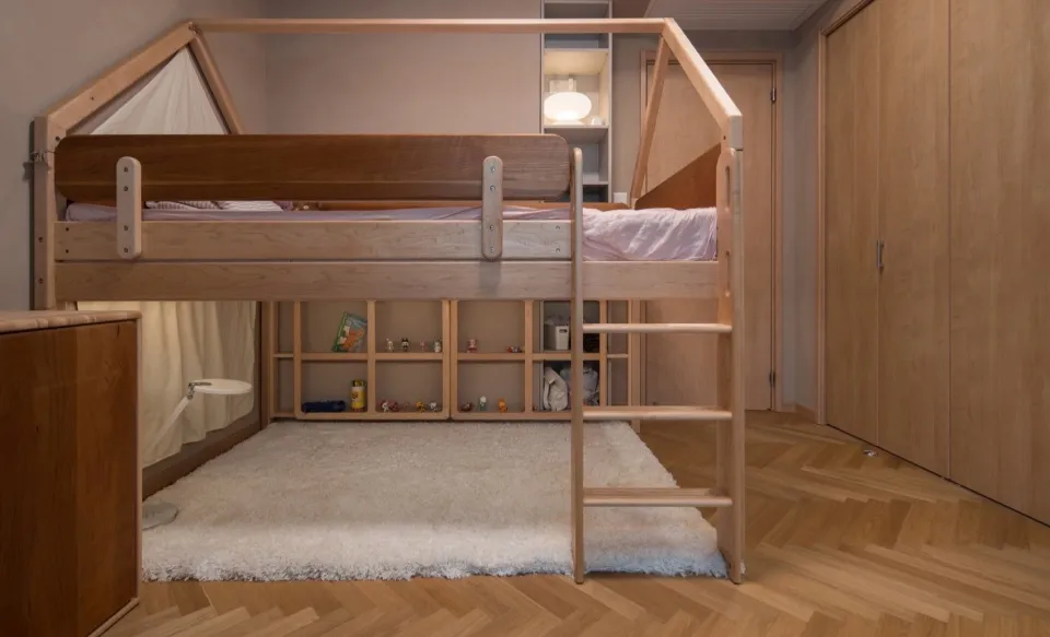 A modern, industrial-style playroom with a wooden bunk bed and a white shaggy rug on a herringbone-patterned wooden floor.