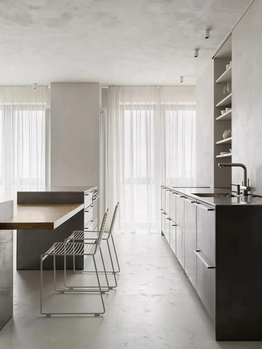 A modern, minimalist kitchen with concrete finishes and a sleek, open layout.