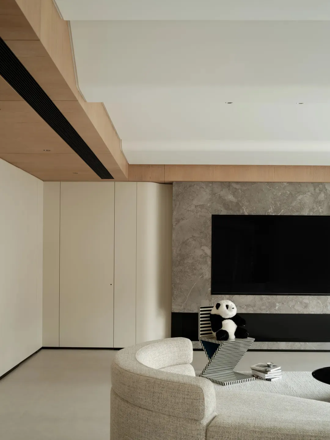 A minimalist living room with marble finish, featuring a white sofa and a black and white striped table.