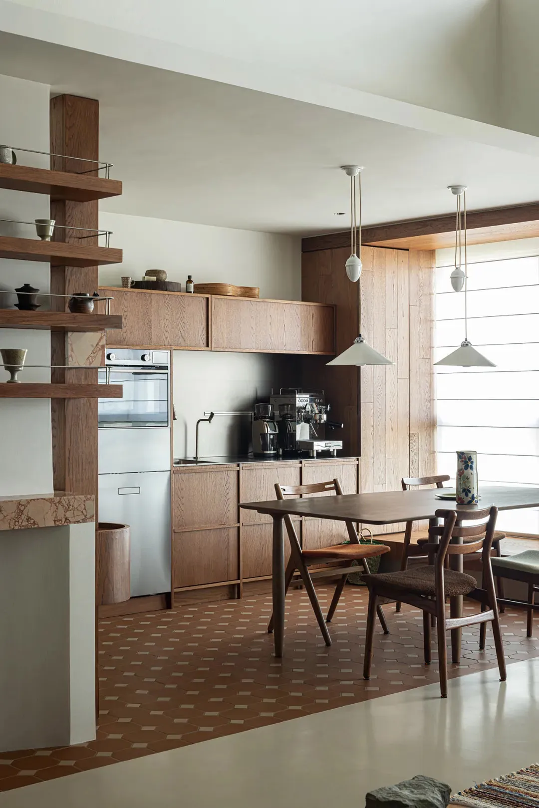 A modern kitchen with wooden cabinets, a wooden table, and pendant lights.