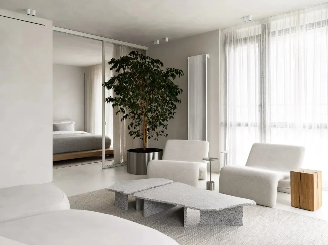 A modern living room with granite furniture, minimalist decor, and a large tree plant.