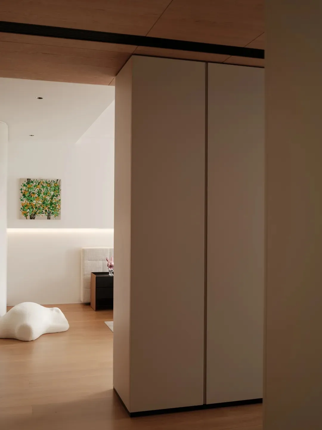 A modern minimalist bedroom with wooden flooring and white furniture.