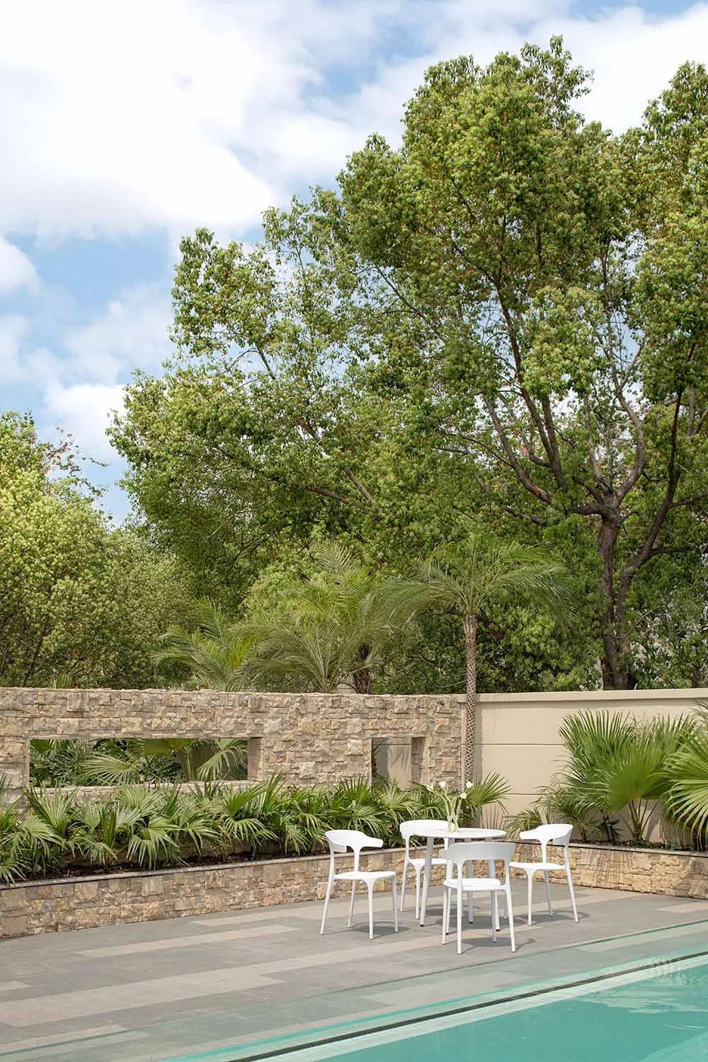 A serene outdoor relaxation space featuring modern furniture, stone and concrete elements, surrounded by lush greenery.