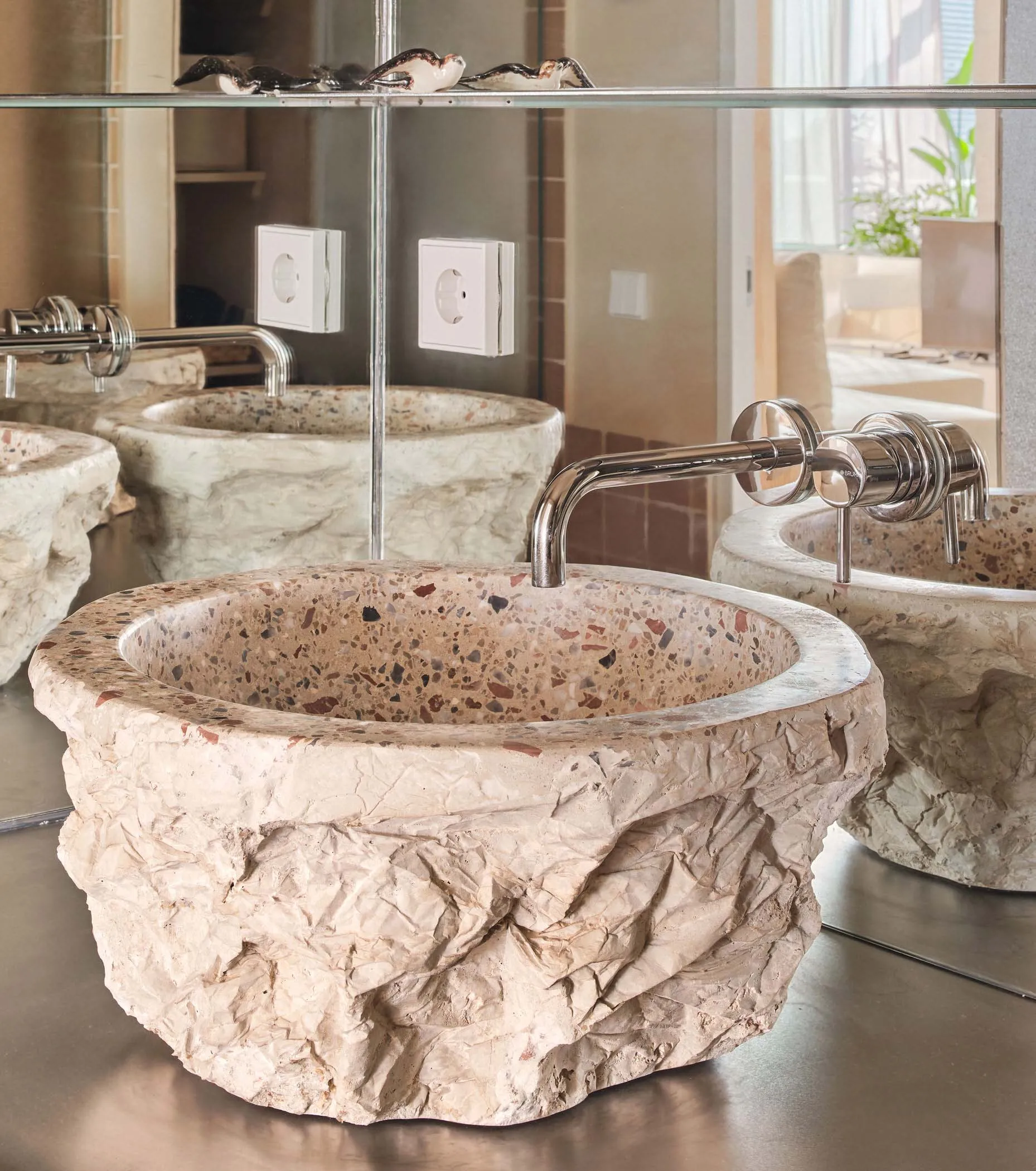 A minimalist bathroom with a terrazzo sink and polished chrome faucet.