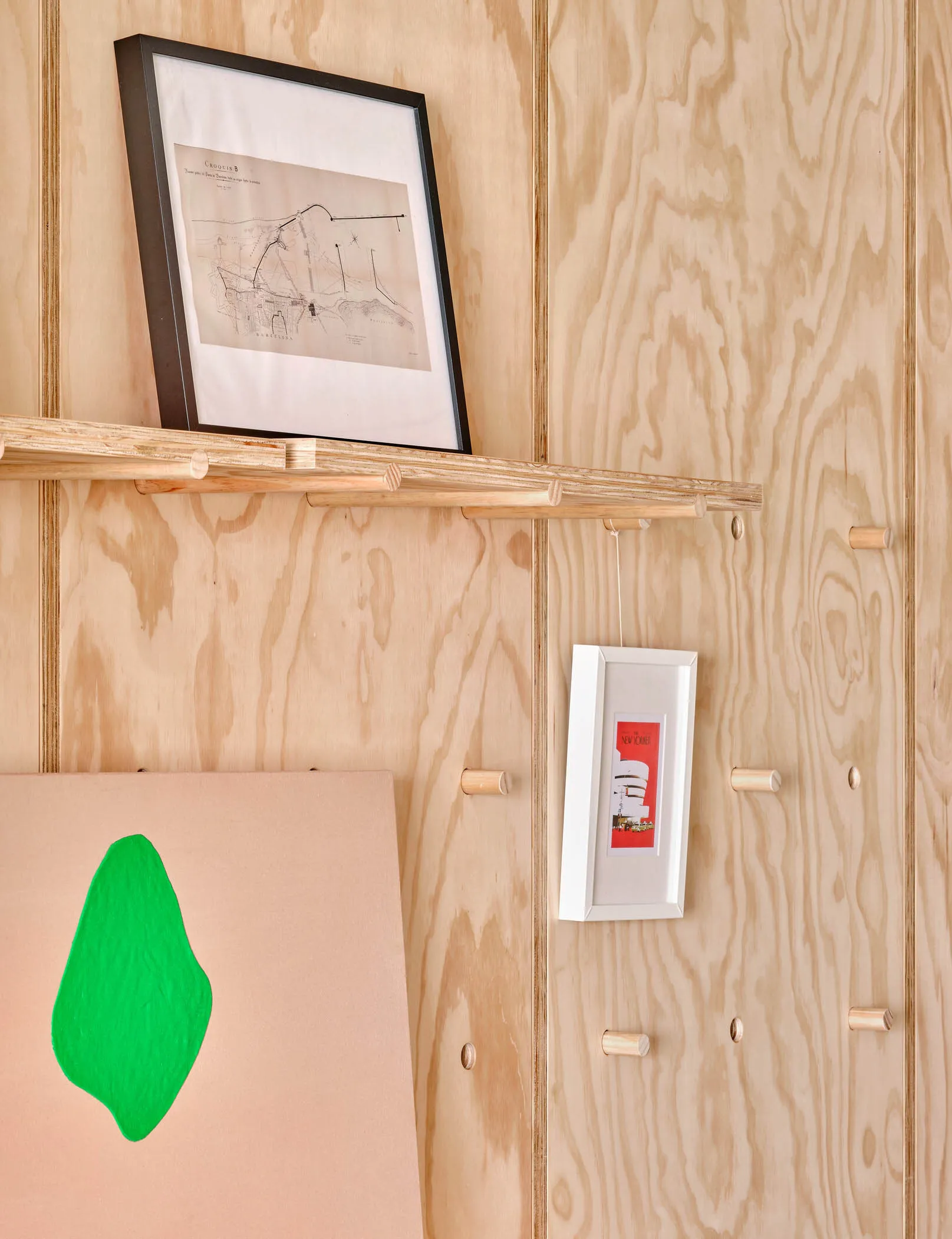 A wooden shelf with framed artwork and a green leaf decoration.