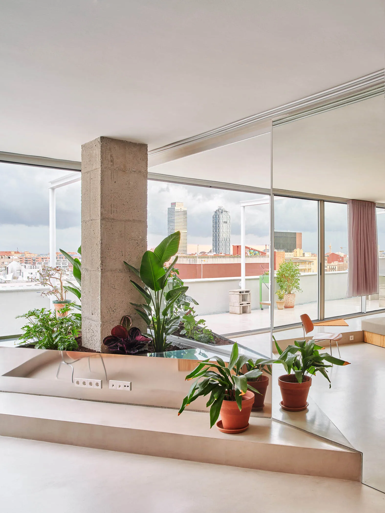 Modern rooftop terrace with concrete pillar and potted plants.
