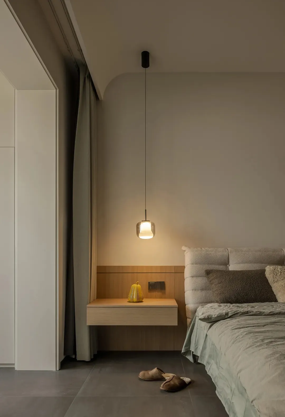 Minimalist bedroom with a wooden floating nightstand and a yellow lantern.