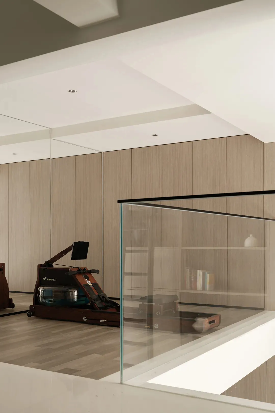 A minimalist gym room featuring wooden panels and a rowing machine.