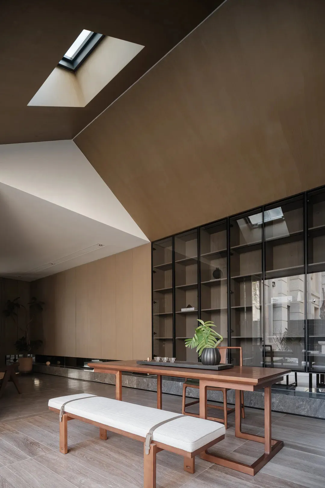 Minimalist living room featuring wooden furniture and glass elements.